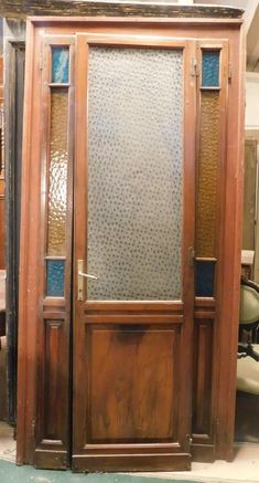 an old wooden door with glass inserts on the front and side panels, sitting next to a barber chair