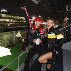 two young women standing next to each other in front of a crowd at night time