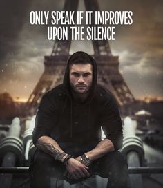 a man sitting in front of the eiffel tower with his hands on his knees