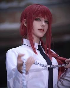 a woman with red hair is holding a phone and looking at the camera while wearing a white shirt and black tie