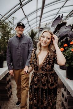 a man and woman standing next to each other in a greenhouse