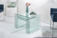 a glass table sitting in the middle of a room with two chairs and a vase on it