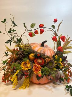 an arrangement of flowers and plants in a pumpkin