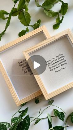 two framed pictures sitting next to each other on top of a table with green leaves