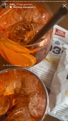 two glasses filled with drinks sitting on top of a table next to a bag of chips