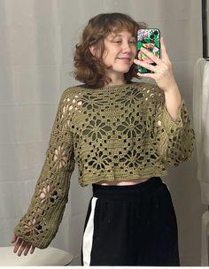 a woman taking a selfie in front of a mirror with her cell phone and wearing a crocheted crop top