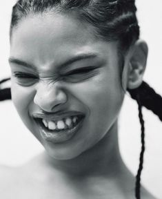 a young woman with her eyes closed and hair in pigtails is smiling at the camera