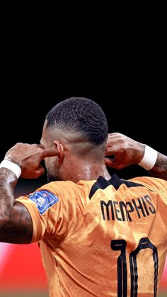 a man in an orange jersey is holding his hands on his head and looking at something