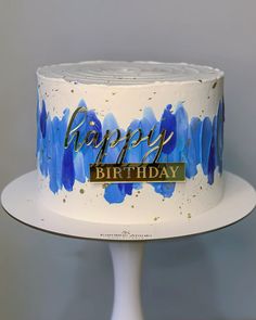 a birthday cake with blue and gold paint splattered on it that says happy birthday