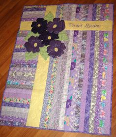 a quilted table runner with purple flowers and words written on the side that says, violet empire