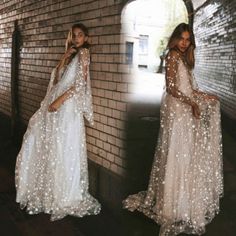 two women in long dresses standing next to each other on a brick wall and posing for the camera