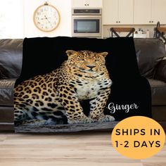 a leopard sitting on top of a couch covered in a blanket with the words ginger ships in