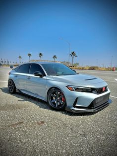 a silver car parked in a parking lot next to palm trees on a sunny day