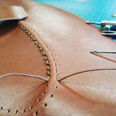 the stitchs are being sewn together to make a leather bag or purse with scissors and thread