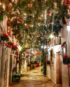 an alleyway with christmas decorations and lights on the ceiling, decorated in red and green