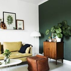 a living room with green walls and white flooring is pictured in this image, there are plants on the wall