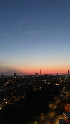 the city skyline is lit up at night, with buildings in the foreground and street lights on either side