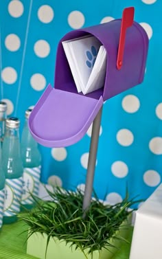 a purple mailbox sitting on top of a green table next to blue and white polka dot wallpaper