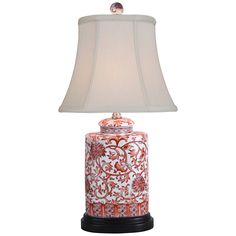 a red and white lamp on a black base with a beige shade over the top