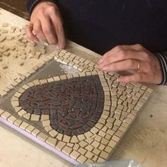 a person is working on a mosaic tile work with scissors and glues to it