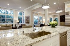 a large kitchen with marble counter tops and white cabinets, along with stainless steel appliances