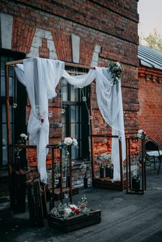 an outdoor ceremony with white draping and flowers on the side of the building