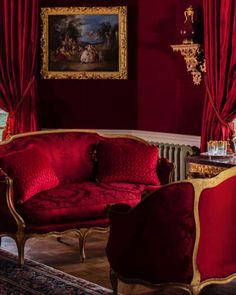 a living room with red velvet furniture and paintings on the wall