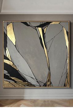 an abstract painting hangs on the wall in a room with hardwood floors and walls painted gray, gold and white