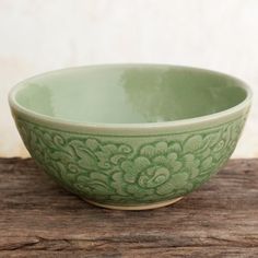 a green bowl sitting on top of a wooden table