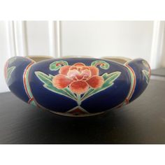 a blue bowl with a flower painted on the side sitting on top of a table