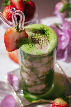 a green drink with strawberries on the rim