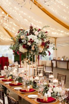 a table set up with candles, plates and flower centerpieces for a wedding reception