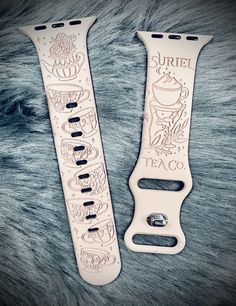 two white watch bands sitting next to each other on a fur covered surface with the words suriel and taco written in curs