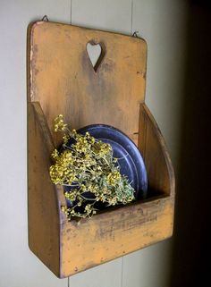 an old wooden shelf with plates and flowers in it