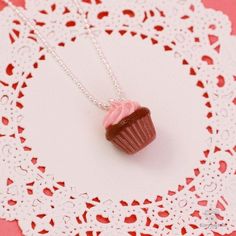 Chocolate and strawberry is a combination that is so delicious, it borders on divine. When you treat yourself to the Scented Strawberry Chocolate Cupcake Necklace, you can surround yourself with these two delicious fragrances and add a splash of color to any ensemble. Carefully handmade to resemble a chocolate cupcake topped with mouthwatering strawberry icing, the pendant is fashioned out of eco-friendly polymer clay. The luscious mix of chocolate and strawberry scents come from fragrance oils Sweet Red Jewelry For Valentine's Day, Sweet Silver Necklace Perfect For Gifts, Kawaii Style Necklaces For Valentine's Day Gift, Handmade Sweet Pink Necklace, Pink Handmade Sweet Necklace, Handmade Pink Sweet Necklace, Sweet Pink Necklaces For Valentine's Day, Sweet Pink Necklace For Valentine's Day, Novelty Pink Necklace For Birthday