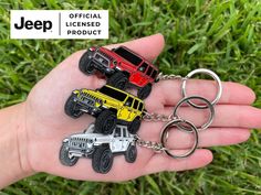 four jeep key chains in the palm of someone's hand that is holding them