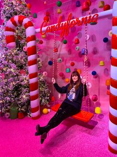 a woman sitting on a swing in front of a christmas tree and candy canes