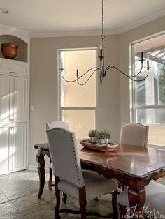 a dining room table with white chairs and a chandelier hanging from the ceiling