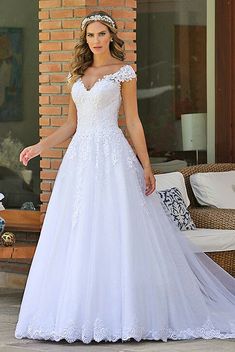 a woman in a white wedding dress standing on a patio with her hands behind her back