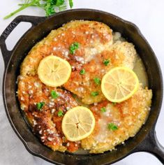 a skillet filled with chicken covered in sauce and topped with lemon slices