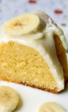 a white plate topped with a slice of cake covered in frosting and banana slices