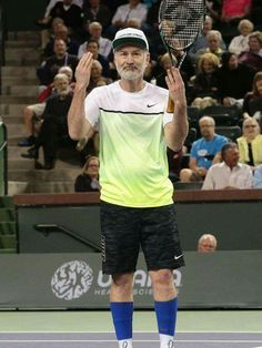 a man standing on a tennis court holding a racquet in the air with both hands