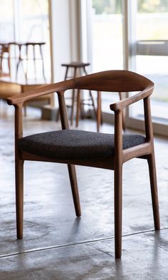 a wooden chair sitting on top of a cement floor next to a large window with lots of windows