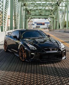 a black sports car is parked on the side of the road in front of a bridge