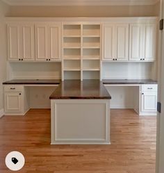 an empty kitchen with white cabinets and wood flooring in the middle of the room