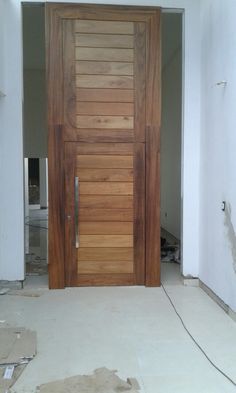 a wooden door in the middle of a room with white walls and unfinished flooring