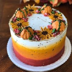 a cake decorated with sunflowers and pumpkins on top of a wooden table