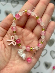 This charming bracelet features a delightful mix of pink, white, and green beads, creating a playful and feminine look.  The bracelet is accented with a cute pink bow charm and a delicate white flower charm, adding a whimsical touch to your style.  A dangling pink bead adds extra movement and charm.  Stretchy and comfortable, this bracelet is perfect for everyday wear or as a sweet gift for someone special.  Add a pop of color and fun to any outfit with this lovely accessory! **Listing is for on Pink Cute Bracelet, Pink Beads Bracelets, Charming Bracelet, Flower Charm Bracelet, Bracelets Design, Beads Bracelet Design, Green Beads, Fancy Jewelry, Pink Beads