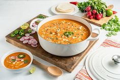 a bowl of soup on a cutting board next to other bowls and utensils