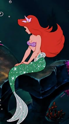 the little mermaid is sitting on top of a rock